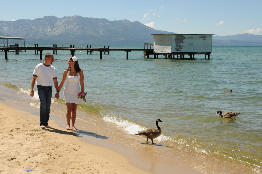 Bride and groom stroll along the shoreline of Regan Beach