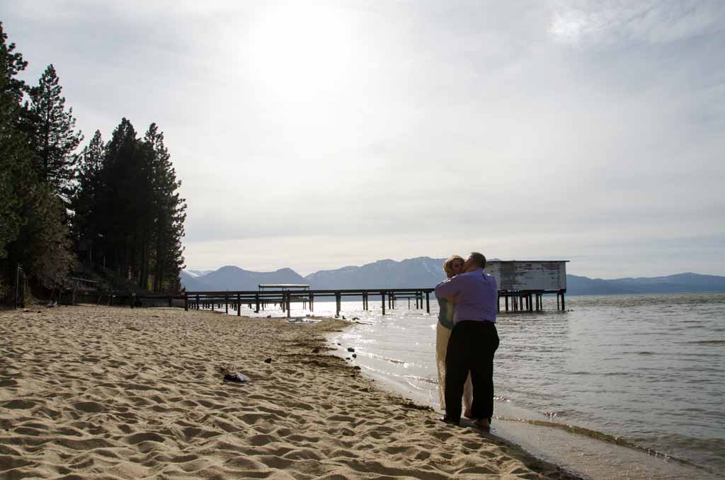 Newly married couple embrace each other by the lake.