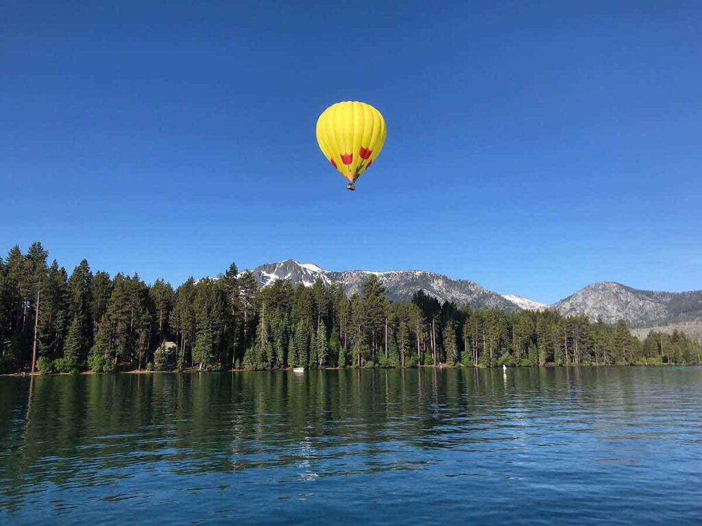 Hot air balloon flying high over the lake and mountaintops