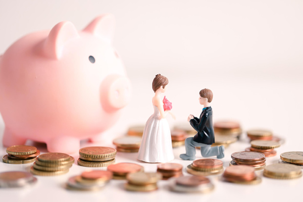 Bride and groom cake toppers next to piggy bank with coins