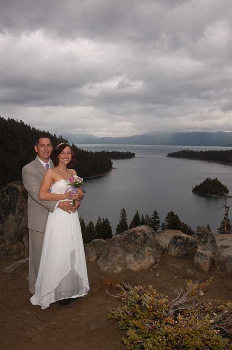 Groom hugs bride on the bluff overlooking the bay