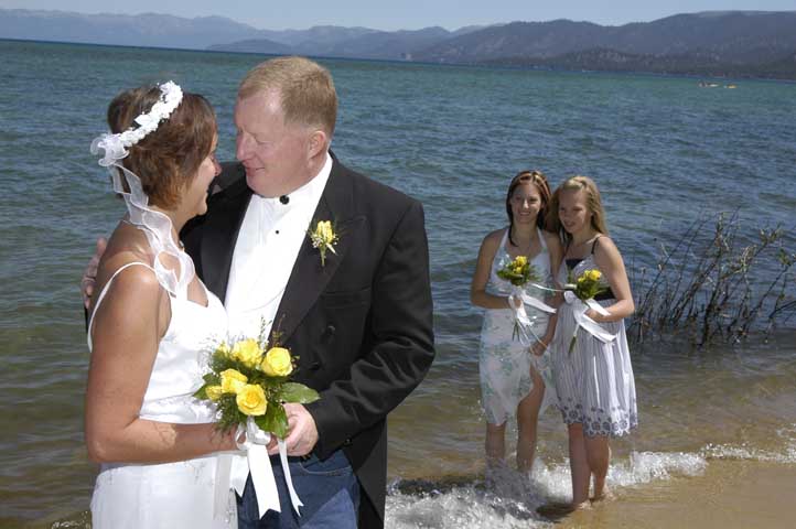 The two young girls look at their mom and dad while standing in the water