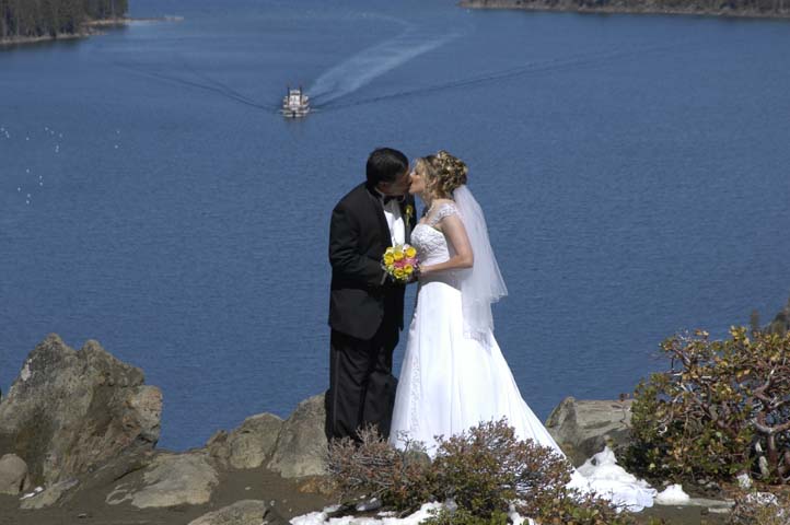 Groom kisses his bride on the bluff that overlooks Emerald Bay
