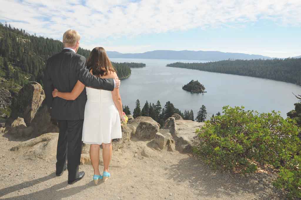 A married couple look outwards towards the lake from the bluff of Emerald Bay