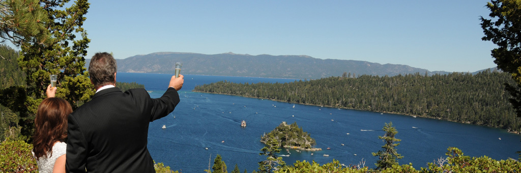 The newly married pair hold champagne glasses high over the bluff of Emerald Bay