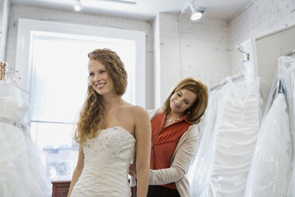 Mother of the bride helps her adjust the bridal gown