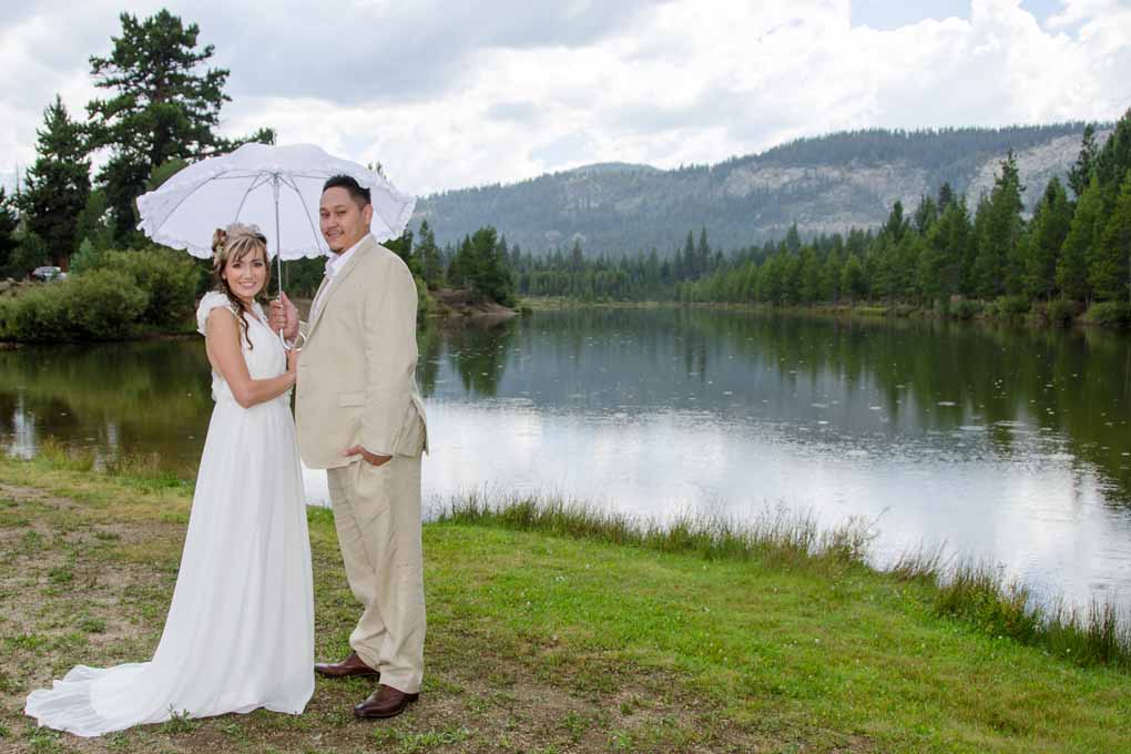Just married and posing with a white umbrella by lake