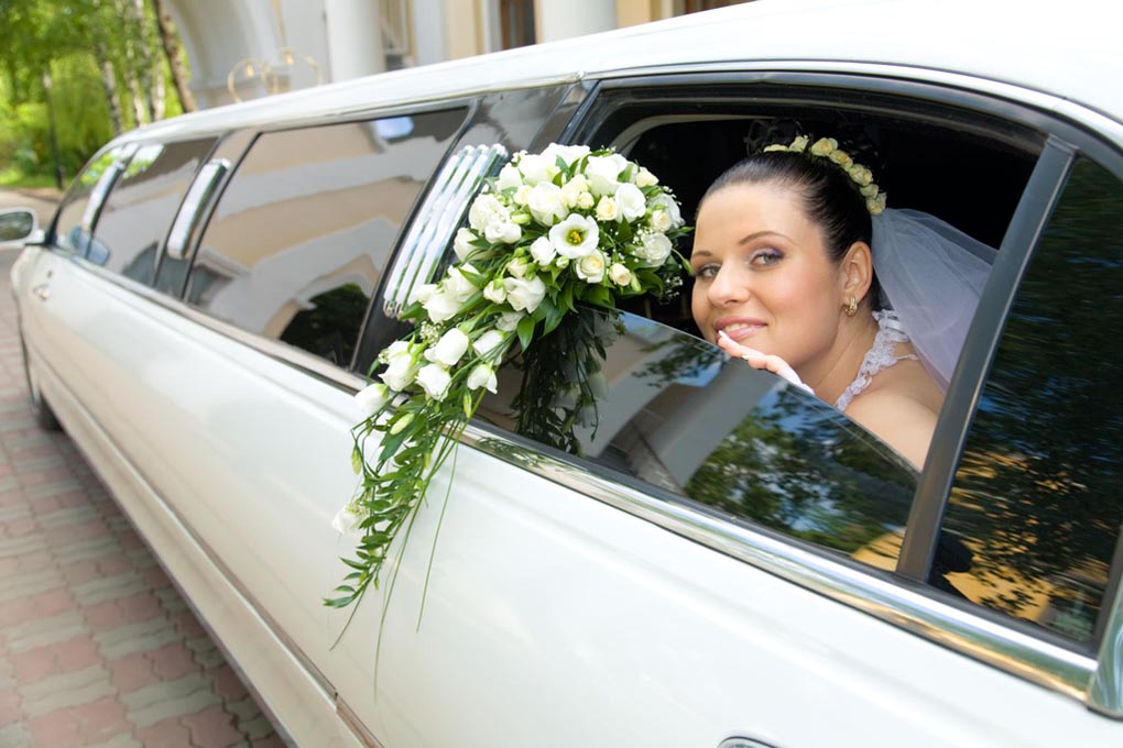 Bride looks out the limousine window with her bouquet