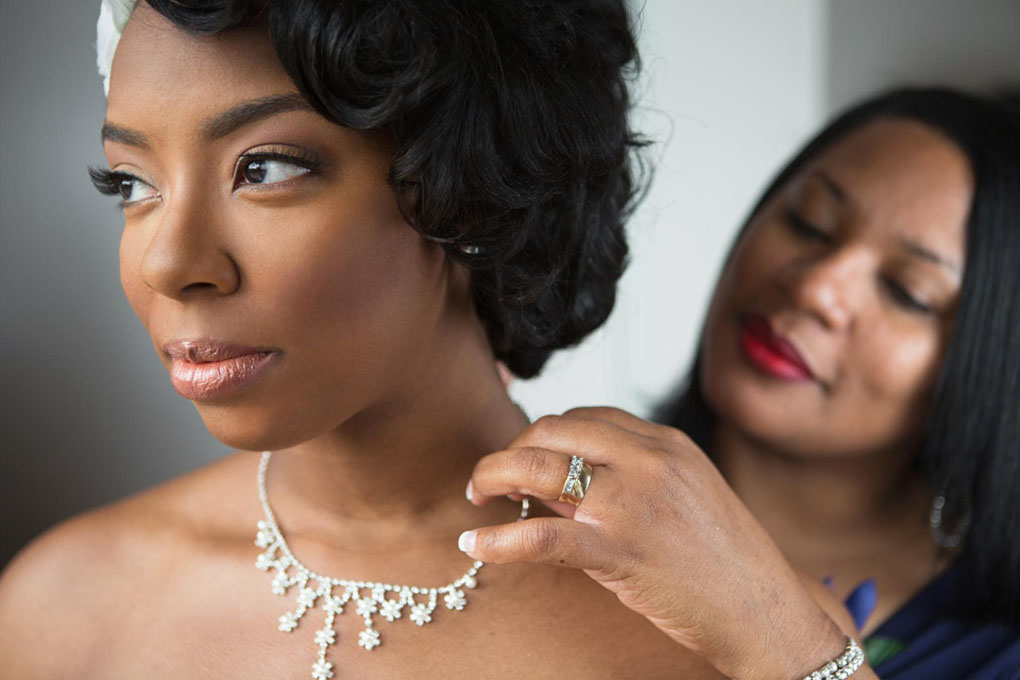 Mother of the bride helps her daughter with her necklace