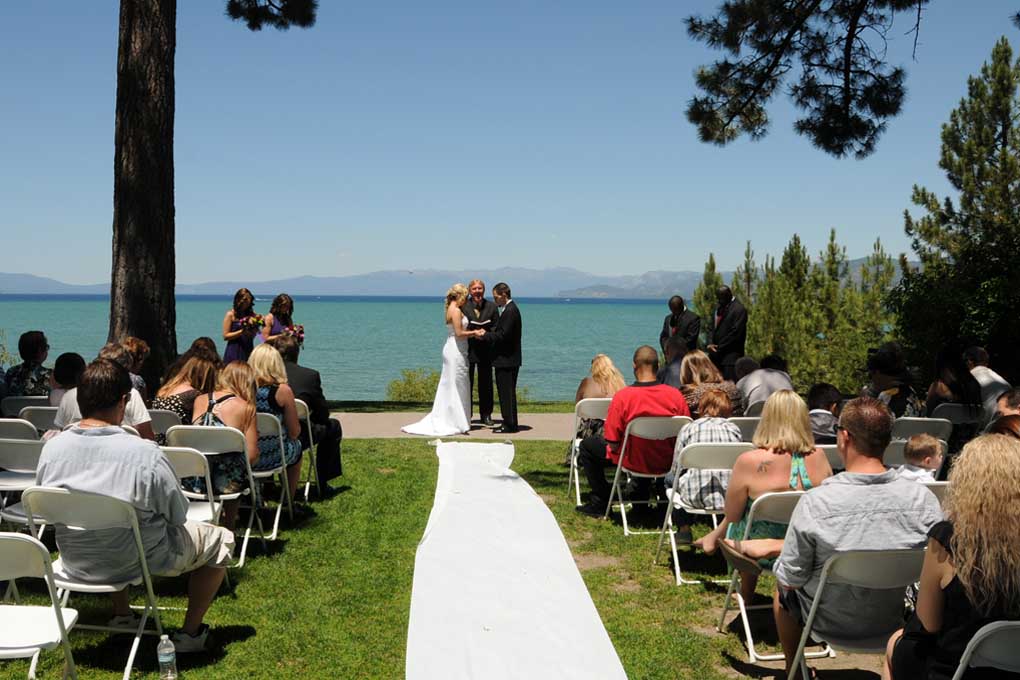 A distant view of the progressing beach ceremony as seen from the end of the aisle runner