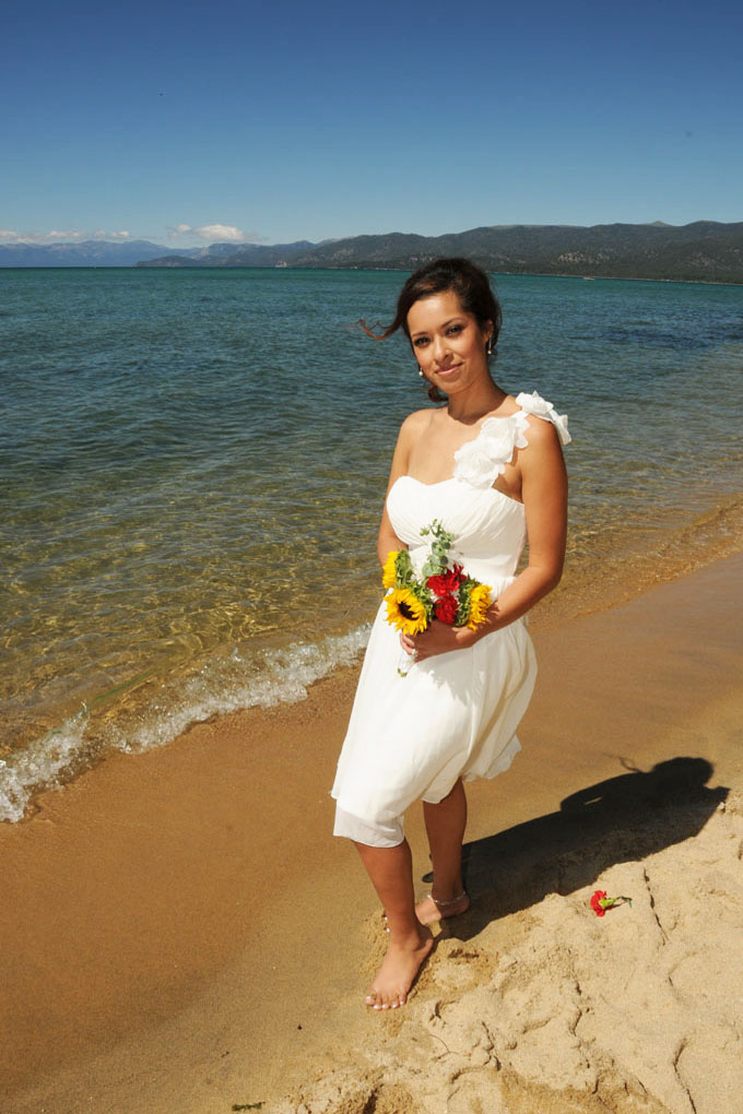 Bride poses with her bouquet while standing next to the shoreline