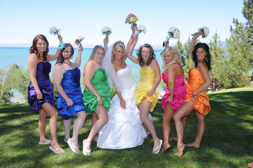 The bridal party girls hold up their bouquets in celebration