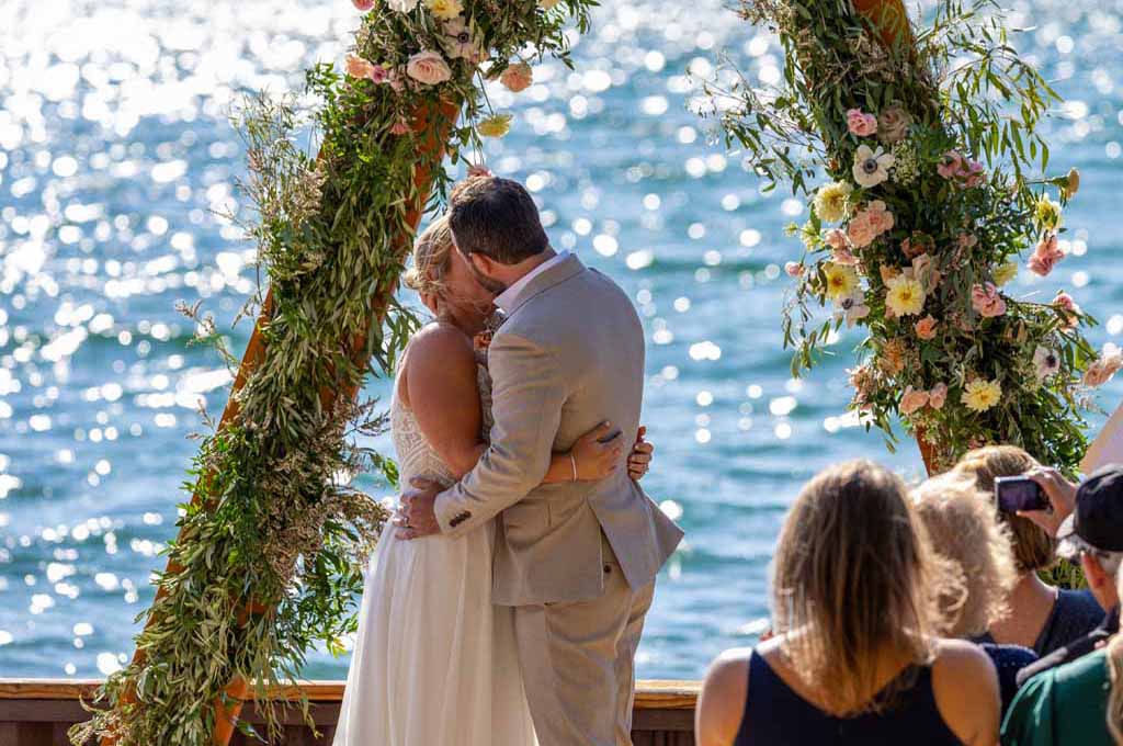 The newly married spouses share a kiss under the arch