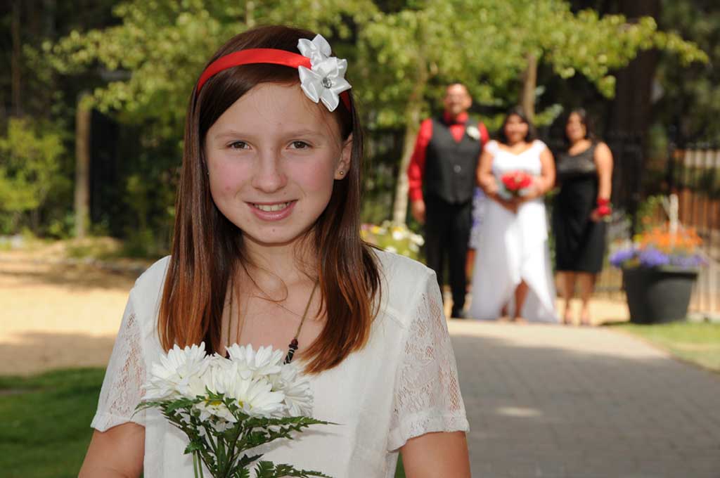 The flower girl walks down the aisle prior to the bride in the background