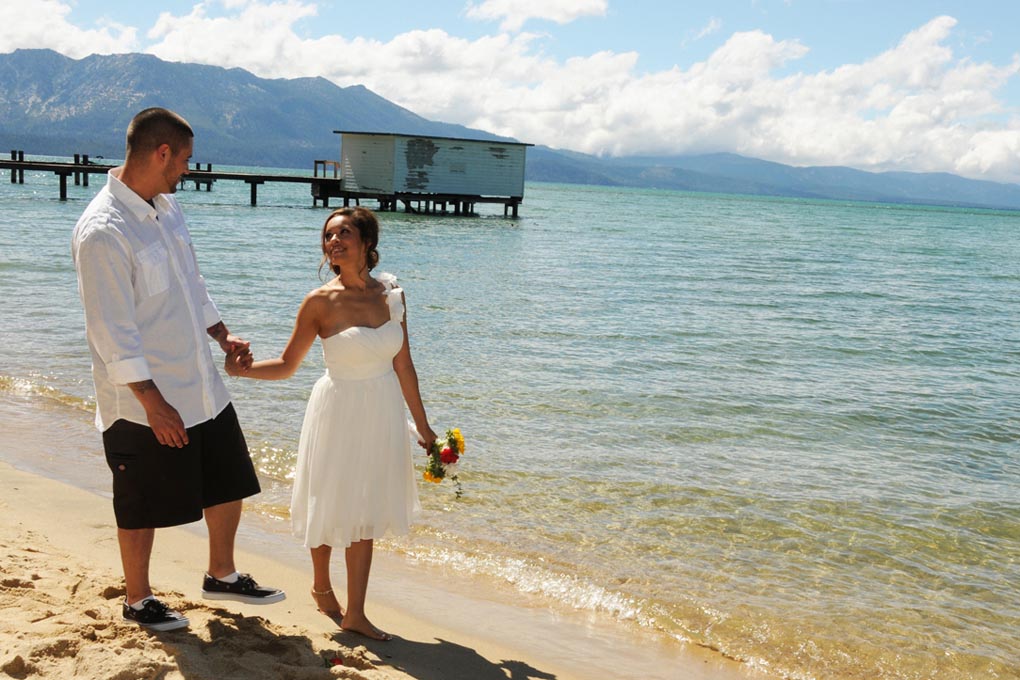 Bridal couple having fun walking along the lake