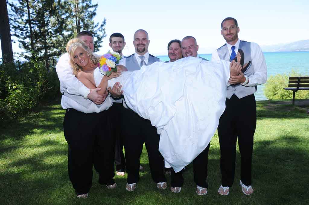The wedding party holds the bride as she lays horizontally
