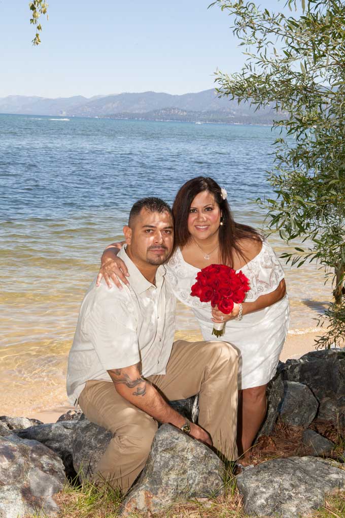 The married couple sitting on a rock by the water