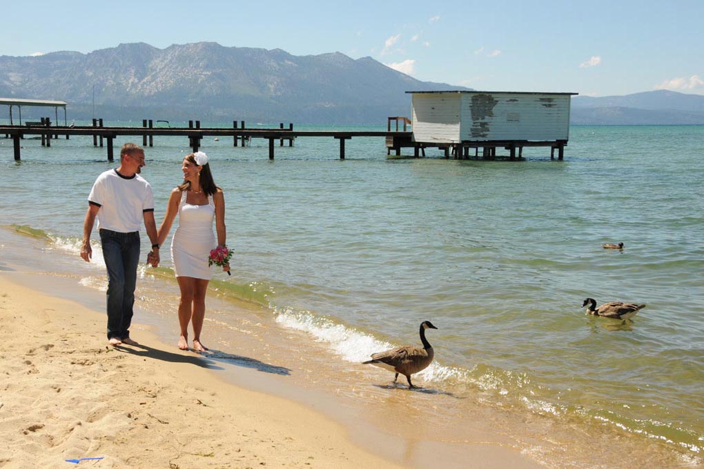 Couple holding hands while walking on the beach and gazing admirably at each other