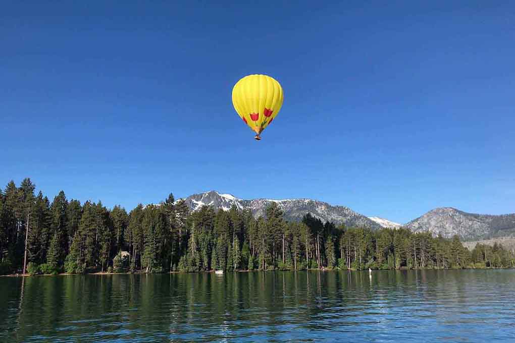 Hot air balloon gliding over the lake and mountains