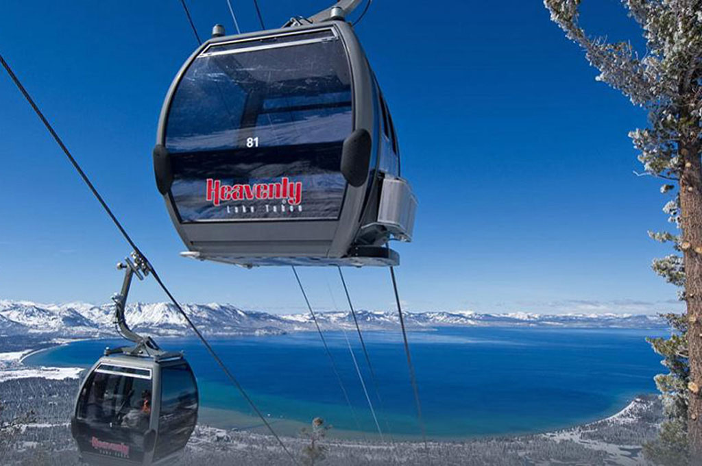 Two elevated gondola cars and a panoramic view of Lake Tahoe and the Sierra Nevada mountain range.